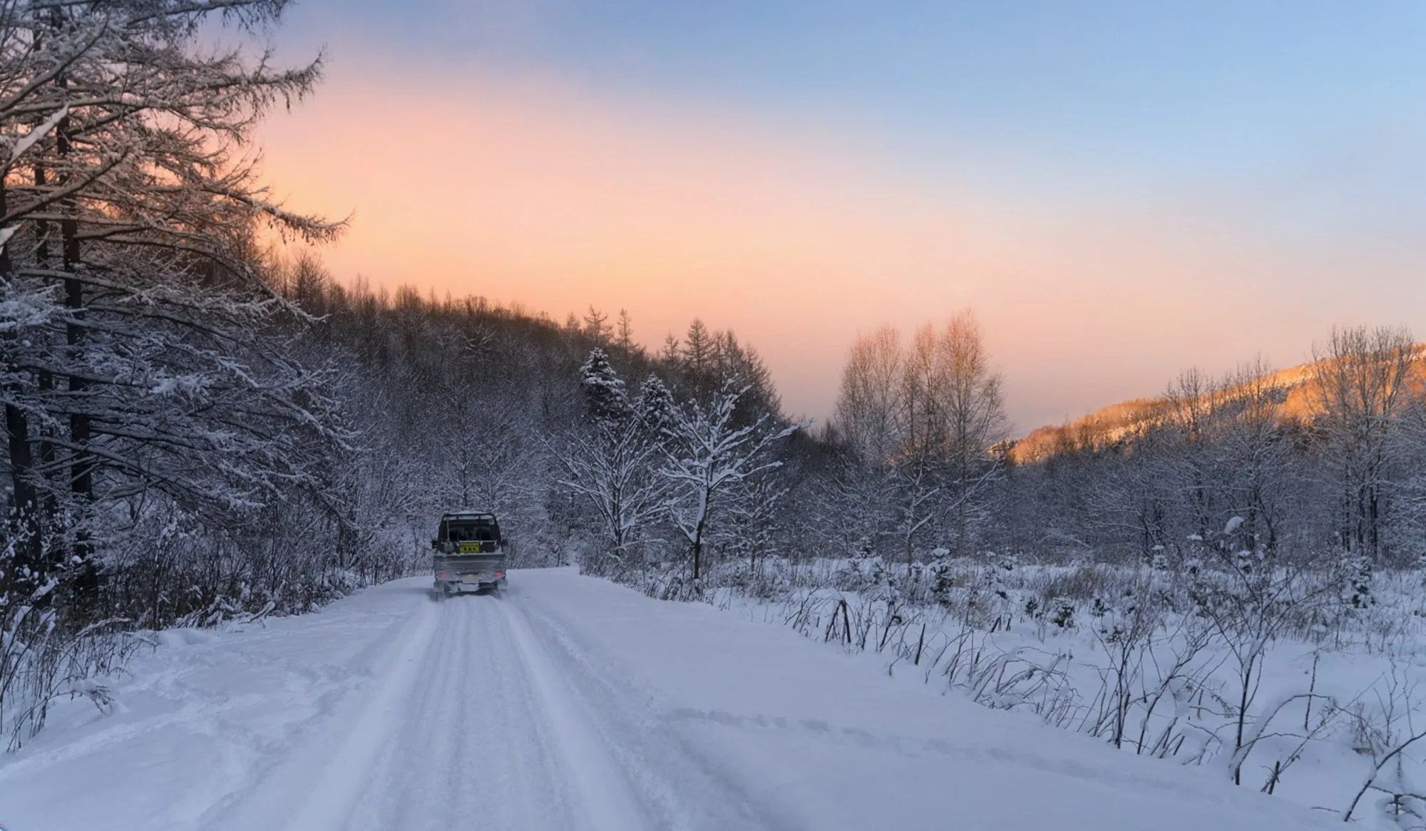 雪道を走る車両とオホーツクの冬景色